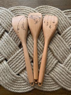 three wooden spoons sitting next to each other on top of a rope covered surface