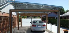 a white car is parked under a metal roof over an enclosed area with wooden posts