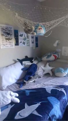 a bed with blue and white bedspread in a room filled with stuffed animals