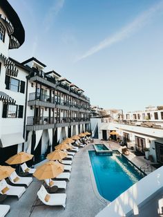 an outdoor swimming pool with lounge chairs and umbrellas next to the hotel's poolside