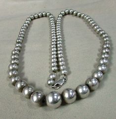 "Graduated sterling silver bead necklace. 25 1/4\" long. The center bead is 12 mm. The smallest beads in back are 6 mm. The beads are strung on chain and have a lobster claw clasp. There is some natural patina on the beads so the look is softer, not too bright and shiny. Good condition. This is a classic timeless look. Good condition. BDS-2" Hand-strung Sterling Silver Necklace In Silver, Hand-strung Sterling Silver Necklace, Sterling Silver Single Strand Beaded Necklace, Classic Round Jewelry With Silver Beads, Classic Silver Single Strand Necklace, Classic Round Beaded Necklace With Sterling Silver Clasp, Sterling Silver Single Strand Beaded Necklaces, Silver Round Beaded Necklaces Hand-strung, Silver Necklaces With 8mm Sterling Silver Beads