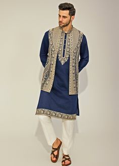 Embrace elegance with the Navy Blue Embroidery Silk Kurta Jacket Set, exquisitely crafted from a premium silk blend for a luxurious touch. The navy blue kurta features a timeless design, with classic embroidery along the collar and edges, offering a sophisticated and sleek silhouette. Paired with a beautifully beige embroidered jacket, adding a layer of refined charm. The deep navy hue contrasts strikingly with the intricate beige embroidery, creating a captivating visual appeal. Completed with Navy Blue Kurta, Navy Blue Embroidery, Beige Embroidery, Classic Embroidery, Blue Kurta, Indian Wedding Wear, Silk Kurta, Blue Embroidery, Embroidered Jacket