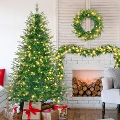 two christmas trees in front of a fireplace with presents under them and a wreath on the mantel