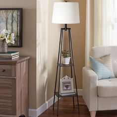 a living room with a white chair and a lamp on a stand in front of a window