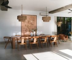 a dining room table and chairs in front of an art work on the wall above it