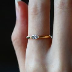 a woman's hand with a diamond ring on top of her finger, showing the side view