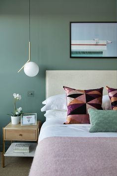 a bedroom with green walls, pink bedding and white linens on the bed