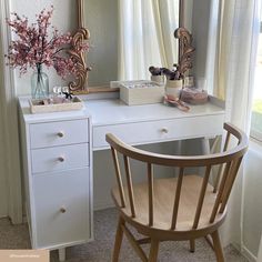 a white desk with a mirror, chair and vase on it in front of a window