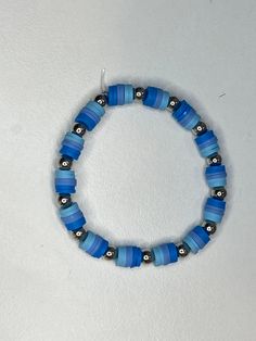 a beaded bracelet with blue and black beads on a white surface, in the shape of a circle