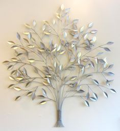 a metal tree with leaves on it is mounted to the wall in front of a white wall