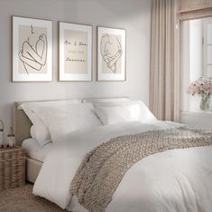 a bed with white sheets and pillows in a bedroom next to two pictures on the wall