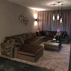 a living room filled with lots of furniture in front of a wall mounted light fixture