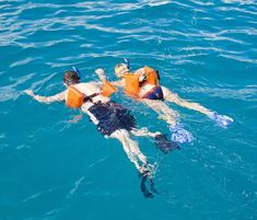 two people floating in the water wearing life vests and snorkeling gear