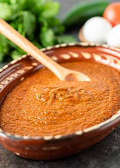 a wooden spoon in a bowl filled with red sauce