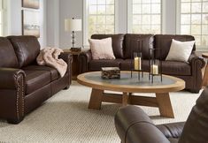 a living room filled with brown furniture and pillows on top of it's couches