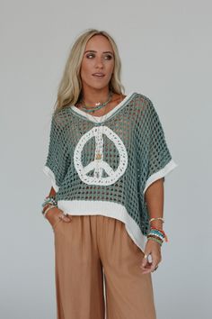 Cozy, cute, and embodying the perfect boho feel, the Peace Oasis Top brings all the peaceful vibes when you wear it! Comfy and cozy open knit fabric throughout Loose and slouchy silhouette for a relaxed fit Classic v-neckline and loose short sleeves for a comfortable, effortless look Contrast knit peace sign patchwork center design Slight high low bottom edge with ribbed knit trim along the bottom hem, sleeves, and neckline Pair with: Eye Of The Sun Padded Bralette, Frenchie Raw Edge Shorts and Bohemian Textured Knit V-neck Top, Bohemian Knit Cover-up For Beach Season, Bohemian Knitted V-neck Top, Bohemian V-neck Knitted Top, One Size Casual Poncho For Spring, Casual V-neck Crochet Top For Beach, Casual V-neck Sweater For Beach, Casual V-neck Festival Cover-up, Casual V-neck Beach Poncho