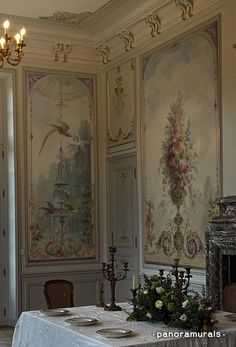 a dining room with wall paintings and chandeliers