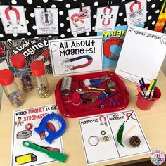 an assortment of magnets, scissors and other items on a table in front of a bulletin board