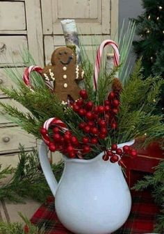 a white pitcher filled with candy canes and greenery