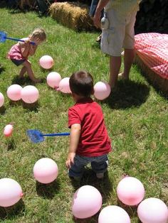 two children playing with balloons in the grass