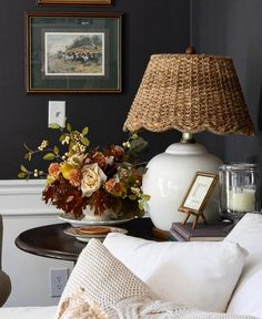 a white lamp sitting on top of a table next to a vase filled with flowers