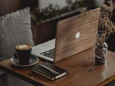 a laptop computer sitting on top of a wooden table next to a cup of coffee