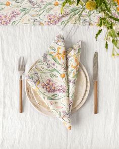 a place setting with floral napkins and silverware