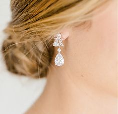 a close up of a woman's ear wearing a pair of white diamond earrings