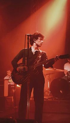 a man standing in front of a microphone and guitar