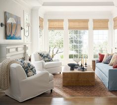 a living room filled with white furniture and lots of window coverings on the windowsill