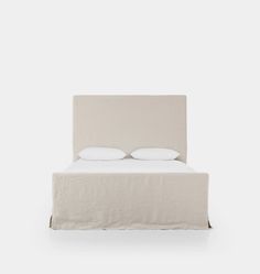 a bed with two pillows on top of it and a white wall in the background