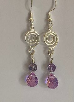 Silver Plated Earrings with Gemcut Teardrop Bead. This teardrop bead has a finish that shines with purple, yellow, green, and blue colors. Fun way to increase your accessory collection. This stunning earrings will make a great birthday gift for a family or friends. It can also be great for a Bridesmaid gift. Materials: 18 mm Sliver plated wire circle swirl 8mm iridescent gemcut teardrop bead  5mm faceted purple bead  Silver plated earlobe  Earrings length: 2" This great piece is carefully packag Purple Sterling Silver Teardrop Dangle Earrings, Purple Teardrop Wire-wrapped Earrings, Purple Teardrop Wire Wrapped Earrings, Handmade Amethyst Teardrop Earrings, Nickel-free Purple Briolette Earrings, Purple Dangle Teardrop Earrings With Ear Wire, Purple Nickel-free Teardrop Dangle Earrings, Purple Teardrop Crystal Earrings In Sterling Silver, Lavender Earrings With Dangling Beads For Gifts