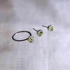 "These stylish earrings have a stunning bright color and the Peridot is surrounded by a halo of shimmering diamonds. Perfect as a gift for girlfriend or wife or mother. Features * Made to Order. * Metal: 925 Sterling Silver * Custom Color: Silver, Gold, Rose Gold * Main Stone: Peridot, 5mm dia Round Shape, 2pcs * Side Stone: Cubic Zirconia Peridot Ring: * Halo Ring: https://etsy.me/2Z81vl7 * Bypassing: https://etsy.me/32VsKR4 Be sure to hit \"favorite\" on the right so it remains in your favorit Birthstone Engagement Rings, Peridot Jewelry, Peridot Earrings, Ring Halo, Stylish Earrings, Halo Earrings Studs, Peridot Ring, Peridot Gemstone, Stylish Earring