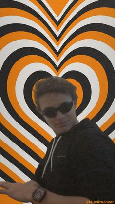 a man wearing sunglasses standing in front of an orange and black heart shaped wallpaper