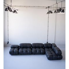 a large black leather couch sitting on top of a white floor next to two lights