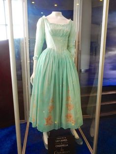 "Inspired by the live action Cinderella character. The soft, delicate dress is lightweight pale blue cotton with a gathered front panel and ruffles at the neckline. Bodice is fully lined in sturdy cotton twill. There's also a white peasant blouse insert at the neckline (not a real separate blouse). The very full skirt has six patches of pink floral appliques. It closes in back with an invisible zipper (you can choose a lace up back if you prefer). Pink apron is included. All seams are serged or Film Costumes, Cinderella Movie, Cinderella 2015, Cinderella Costume, Cinderella Dresses, Lily James, Disney Dresses, Movie Costumes, Peasant Dress