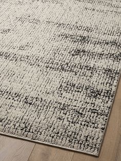 a white and black area rug on top of a wooden floor next to a hardwood floor