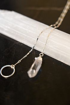 A Quartz necklace unlike any other! This beautiful & timeless Quartz lariat necklace weaves through the circle, allowing you to adjust where the circle sits on your chest. Quartz is the Power Stone, helping you see the Vision you are creating for your life and walk that path with crystal clarity. Pair this gorgeous lariat necklace with our Circle of Life Necklace. Clear Quartz pendant approximately 3/4" in length Sterling silver bar chain and circle ring Necklace is a singular chain without a cl