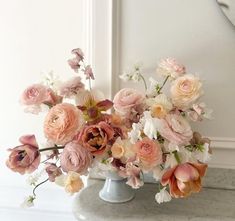 a vase filled with pink and white flowers on top of a marble counter next to a mirror