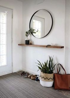 a white room with a mirror, potted plant and shoes on the floor in front of it