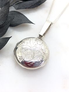 A Lovely Vintage Sterling Silver Round Locket.  Beautifully hand engraved on the front and is plain polished on the back.  There is no hallmarks but has been acid tested and guaranteed to be sterling silver.  This locket has a very unusual extra long top bail, not sure why, maybe to wear with a wide collar or ribbon.  It's in perfect working condition, it opens and closes perfectly with a Click!  Inside it has both original frames, plastics and original paper for your photos.  The locket measure Classic Silver Engraved Necklace, Antique Silver Engraved Locket Necklace For Memorial, Engraved Antique Silver Locket Necklace For Memorial, Vintage Sterling Silver Engraved Locket Necklace, Vintage Engraved Sterling Silver Locket Necklace, Classic Stamped 925 Medallion Jewelry, Silver Etched Round Pendant Jewelry, Antique Sterling Silver Etched Locket Necklace, Antique Etched Sterling Silver Locket Necklace