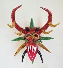 a red mask with horns and spikes on it's head is hanging from the wall