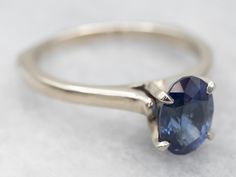 This is a well-proportioned ring, classic and sophisticated. The brightly polished sides have a great heft to them, and this is comfortable on the finger, with a rich feel. We've set the center with a bright blue Ceylon sapphire that has glittering navy and cobalt highlights and plenty of sparkles.Metal: 14K White GoldGem: Sapphire 1.85 CaratsGem Measurements: 6.2 x 8.6 mm, OvalAccents: Diamond .01 Carats, J in Color, I in ClarityRing Size: 9Marks: "14Kt" Stamped on the inside band Classic Sapphire Ring In 14k White Gold, Classic Oval Sapphire Ring With Prong Setting, Classic Oval Sapphire Ring With Polished Finish, Classic Sapphire Birthstone Ring, Classic Oval Sapphire Ring, Classic Sapphire Halo Ring, Classic Blue Sapphire Ring In 14k White Gold, Classic Tanzanite Solitaire Sapphire Ring, Classic Sapphire Tanzanite Solitaire Ring