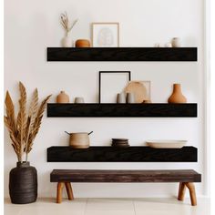 two black shelves on the wall with vases and other items in front of them