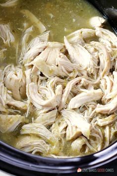 a slow cooker filled with chicken and broth sitting on top of a table