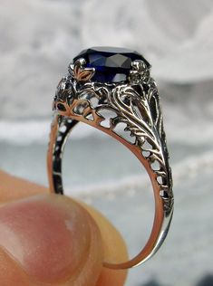 a close up of a person holding a ring with a blue stone in the middle