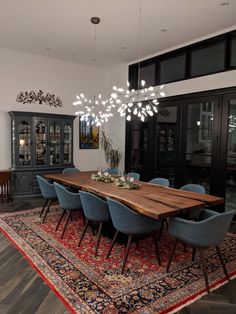 the dining room table is surrounded by blue chairs and an area rug that matches the wooden floor