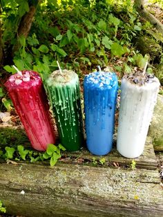 four different colored candles sitting on top of a log