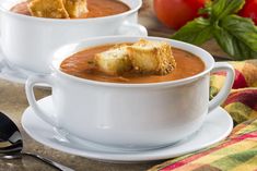 two white bowls filled with soup and croutons