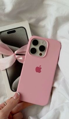 a pink iphone case sitting on top of a white bed next to an empty box